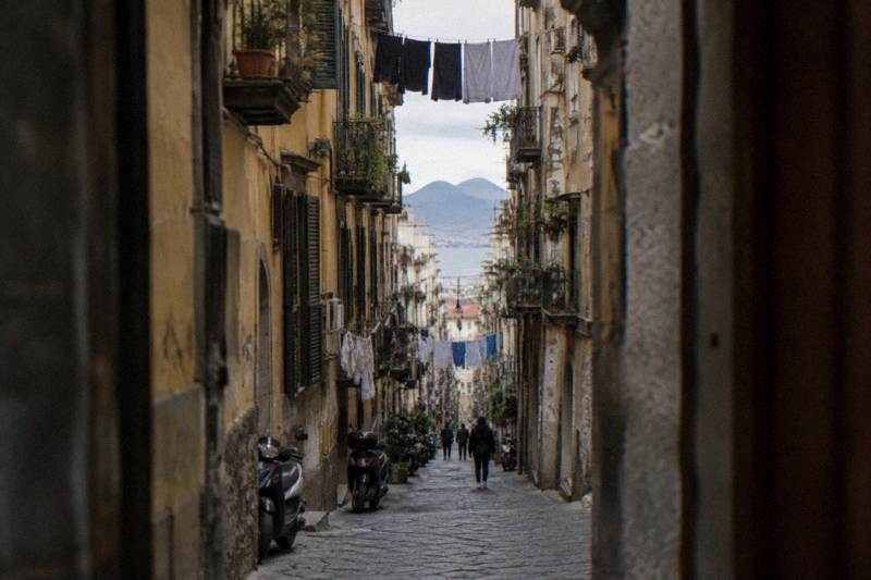 A long narrow street between tall old buildings in central Naples