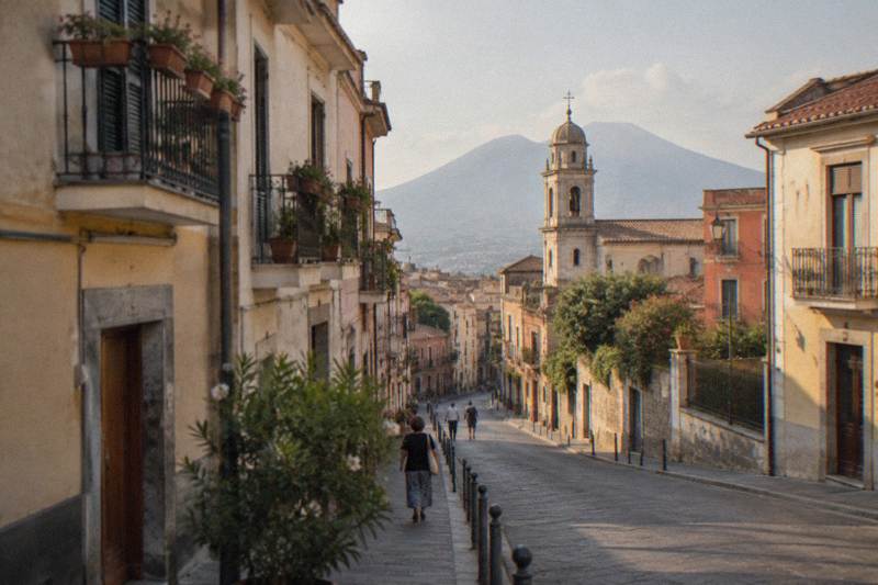 A street of pale buildings leading to a church tower in modern Pompei