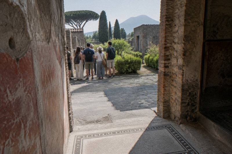 The entrance passage of a small Roman house at Pompeii, with a small group of visitors