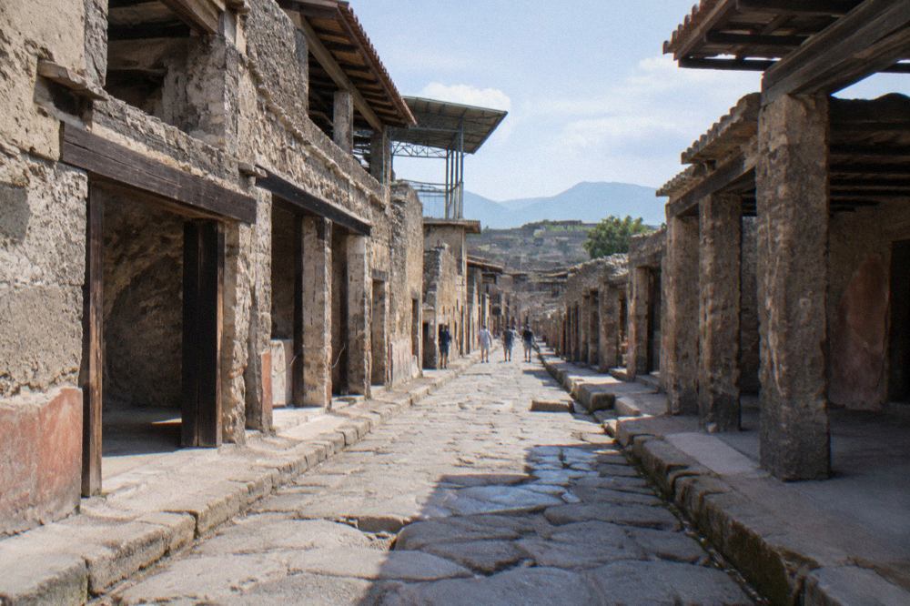 Ancient stone street with worn cart ruts running between excavated walls under a clear sky