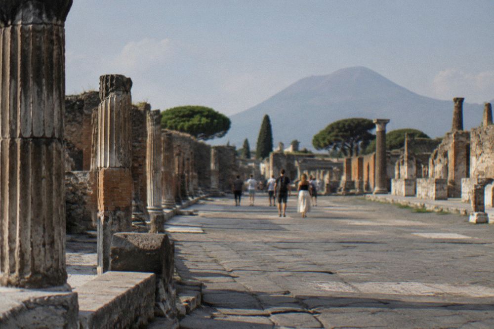 Basalt stone road in Pompeii with cart ruts and ruined brick facades in low sunlight