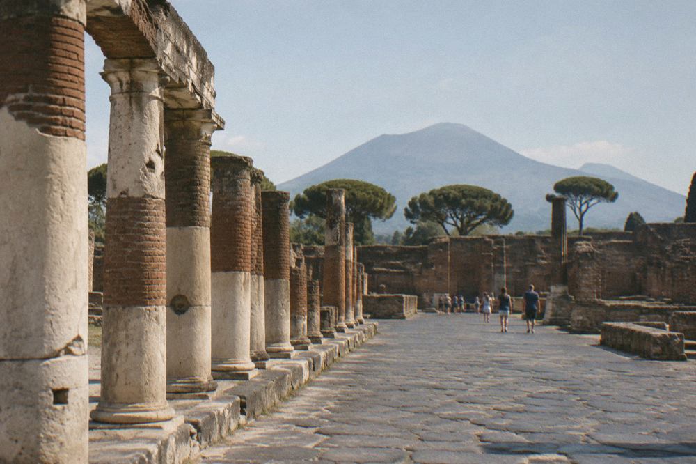 A quiet stone-paved Roman street in Pompeii lined with ancient walls under a clear sky