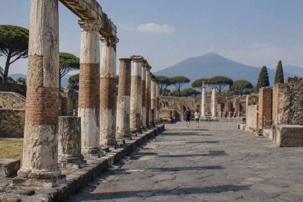 An ancient stone-paved Roman street with worn cart ruts and ruined walls under a clear sky
