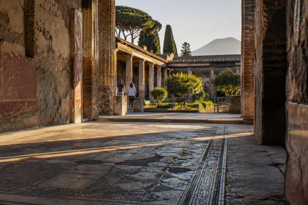 A long straight ancient street in Pompeii lined with stone walls under a clear sky