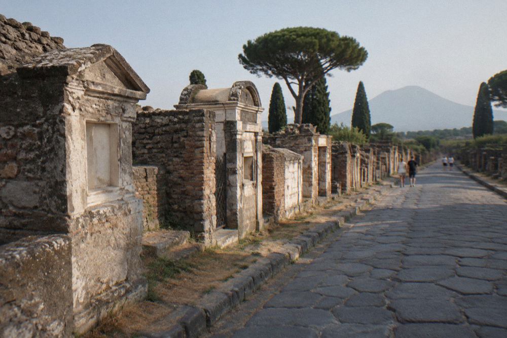 Sunlit Roman stone street with worn wheel-rutted paving under a clear sky at Pompeii