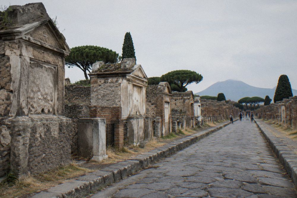 Stone-paved Roman street at Pompeii with low morning light along ruined walls