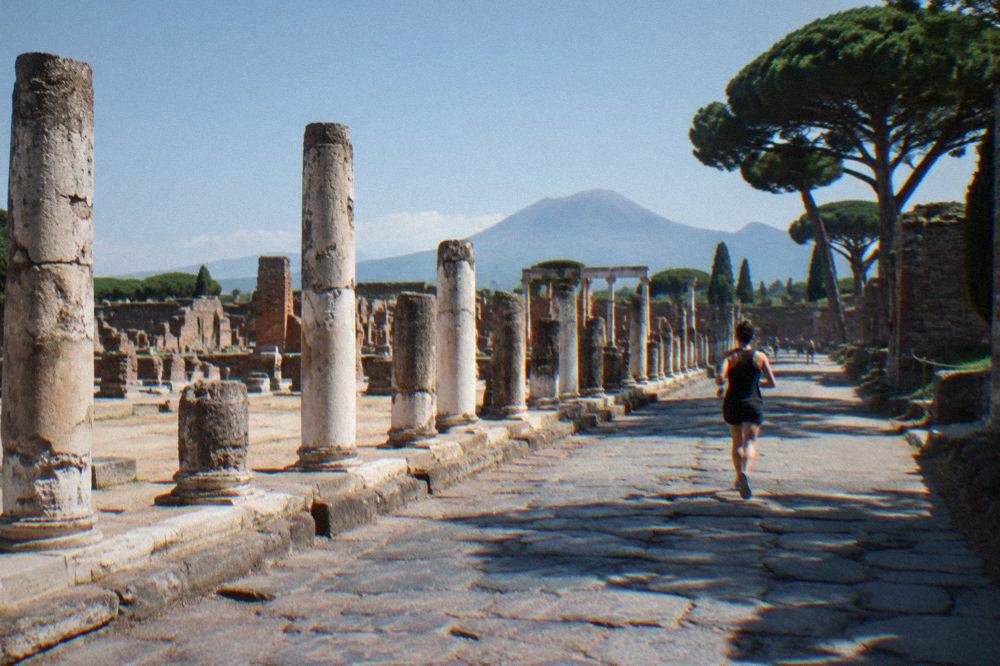 Empty ancient stone street in Pompeii with worn stepping stones and ruined walls under a clear sky