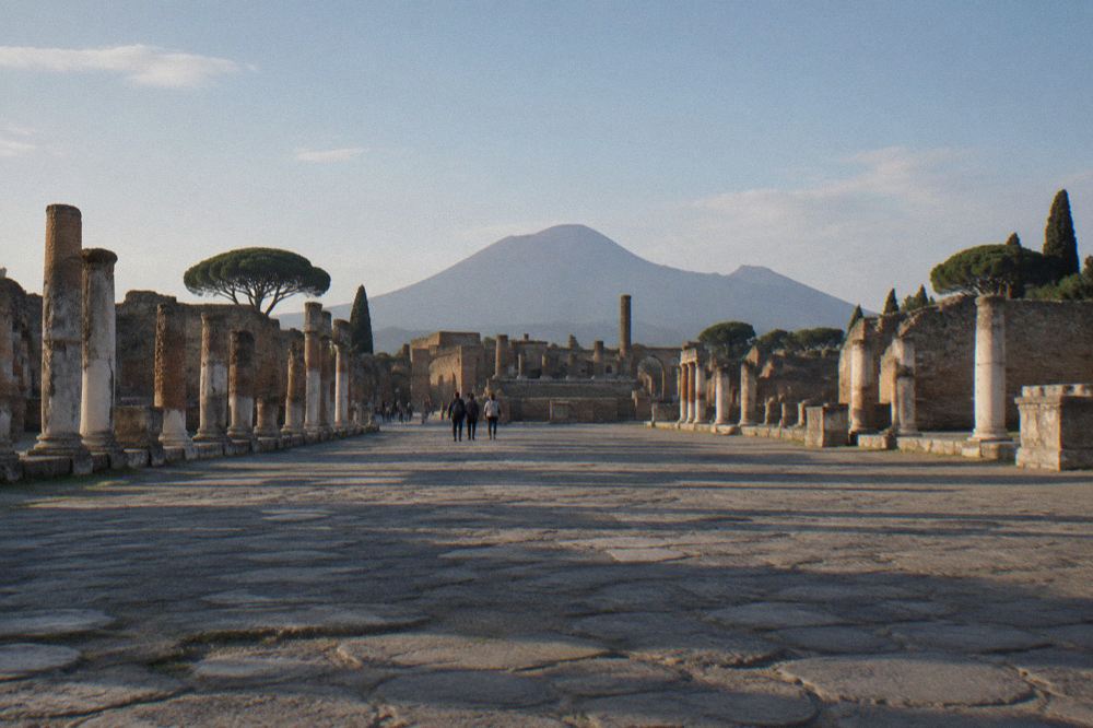 A narrow excavated street in Pompeii lined with stone walls under an open sky