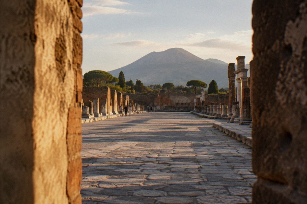 Worn basalt road with stepping stones between ruined walls in Pompeii
