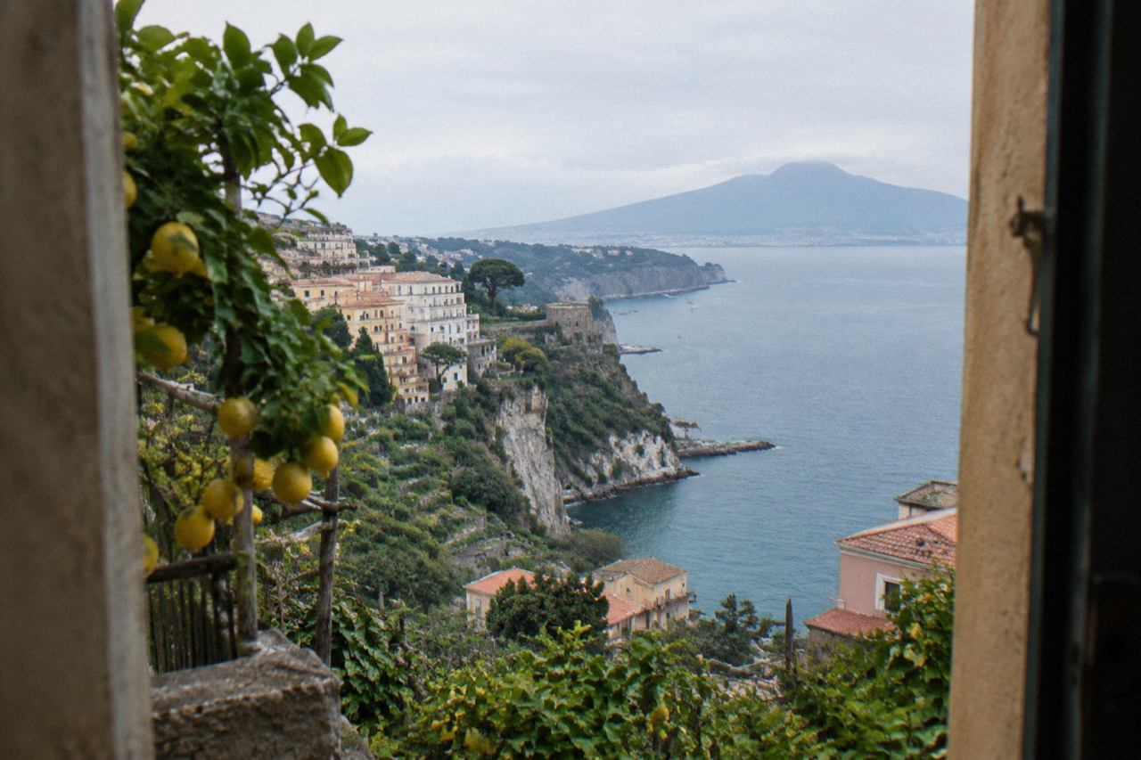The cliffside town of Capri above a calm blue bay with small boats near the shore