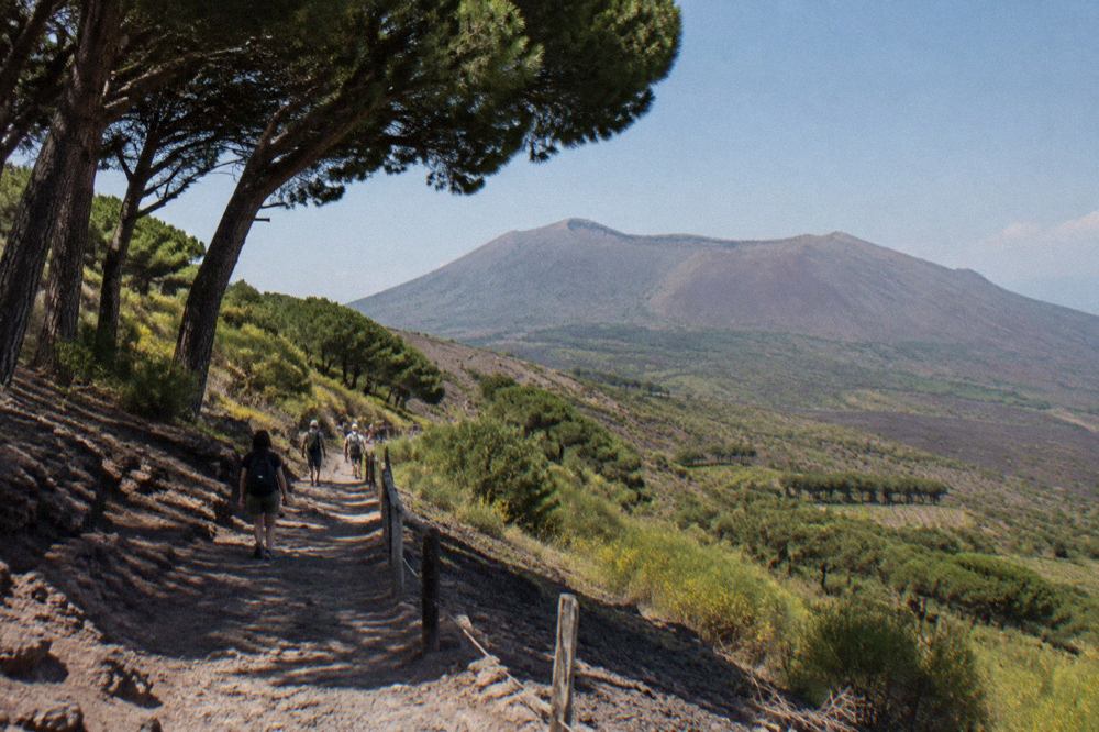 Stone street in the ancient city of Pompeii with Mount Vesuvius rising in the background under a clear sky