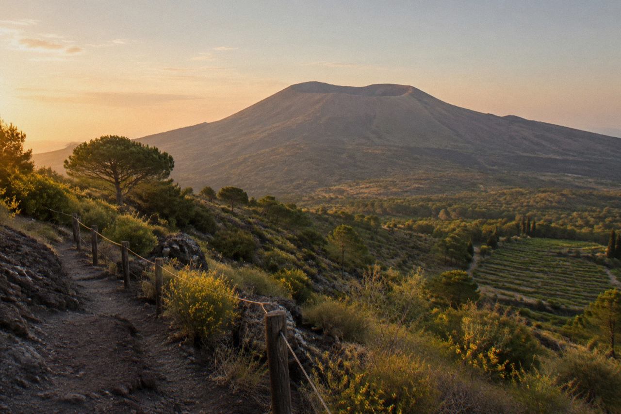 Stone street in the ancient city of Pompeii with Mount Vesuvius rising in the background under a clear sky