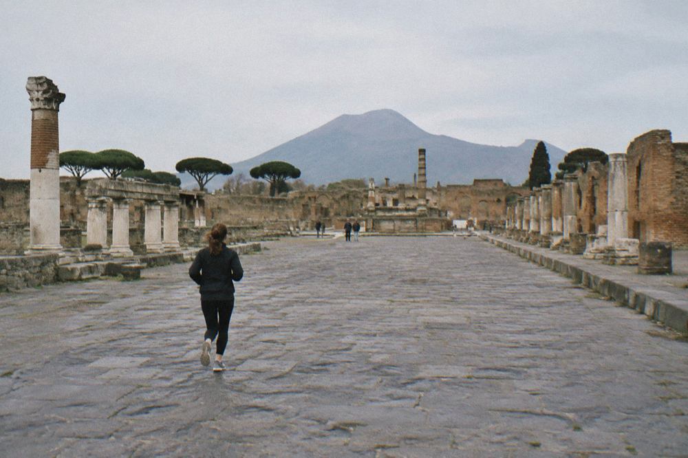 Ancient stone street in Pompeii with worn paving stones and ruined walls under a clear sky