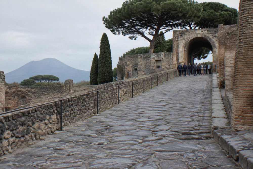 Ancient stone street in Pompeii with worn stepping stones and ruined walls under a bright sky