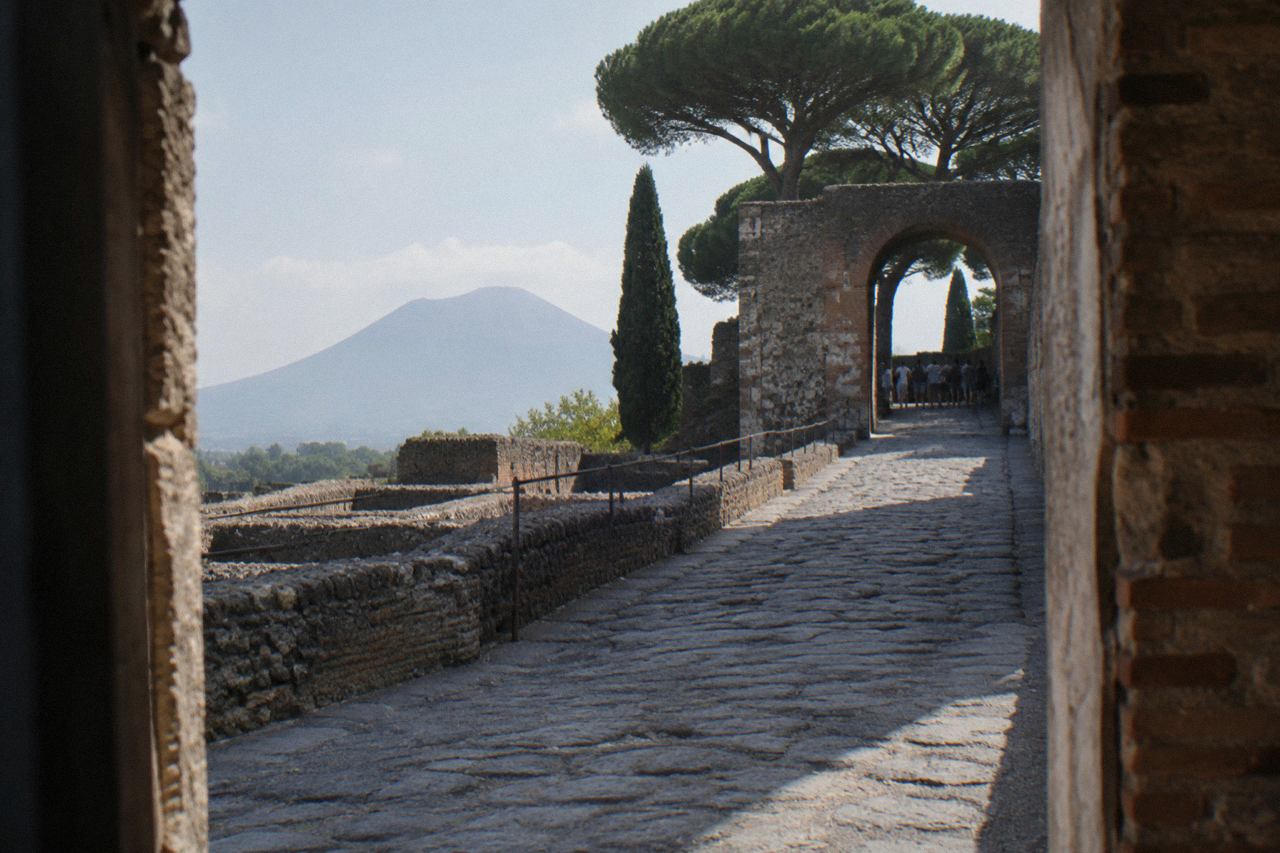 Ancient stone street in Pompeii with Mount Vesuvius rising in the distance under a clear sky