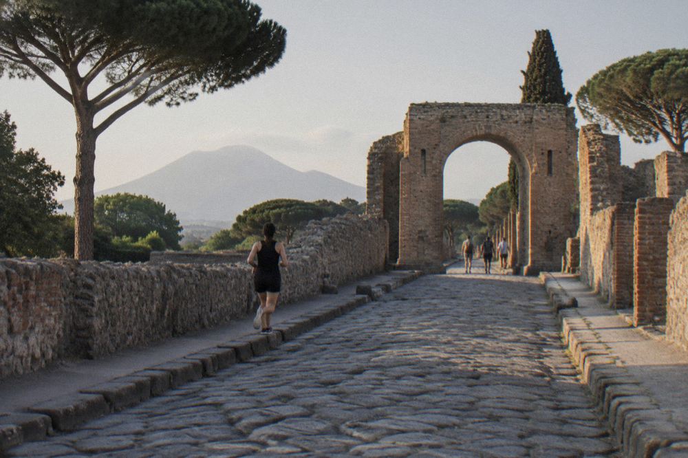 Wide ancient Roman forum square with column stumps and distant mountain slope