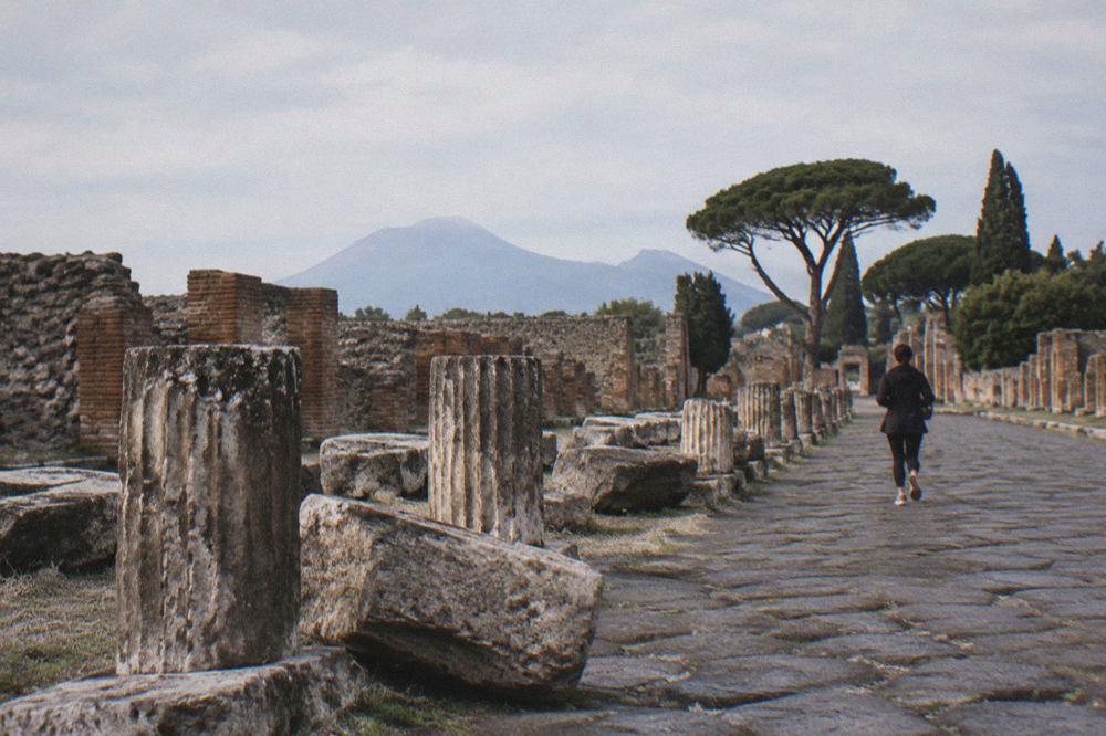 Ancient stone street in Pompeii with wheel-worn paving stones and ruined walls under a clear sky