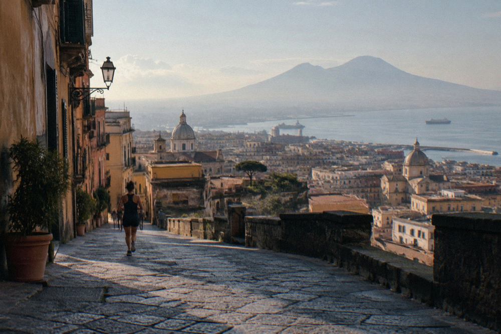 A narrow sunlit Naples alley with weathered ochre buildings and hanging laundry