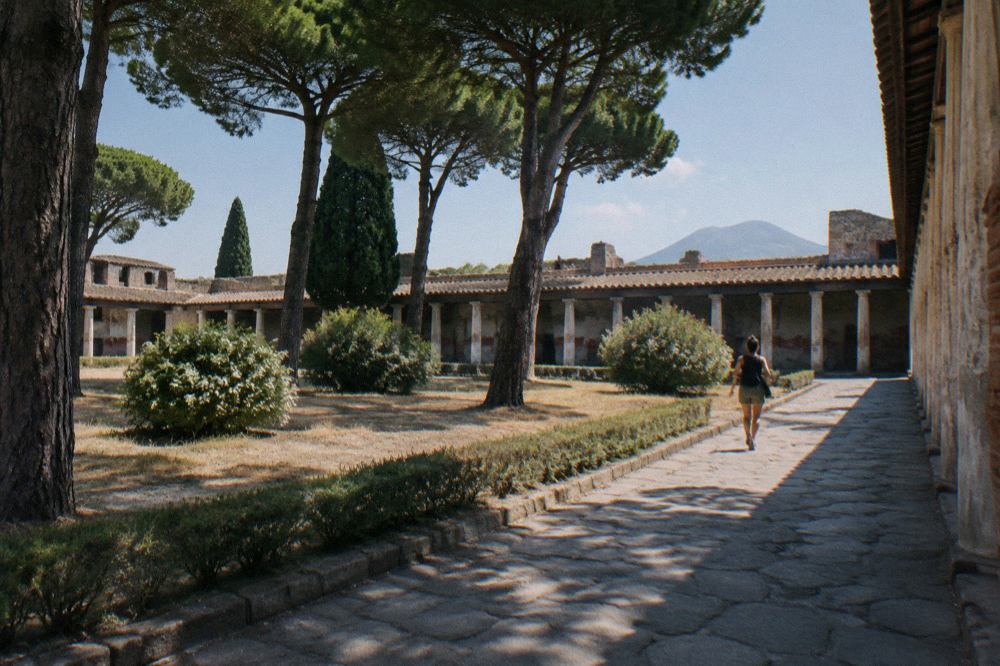 Shaded souvenir stalls and stall awnings along the street outside an entrance to the ancient city of Pompeii