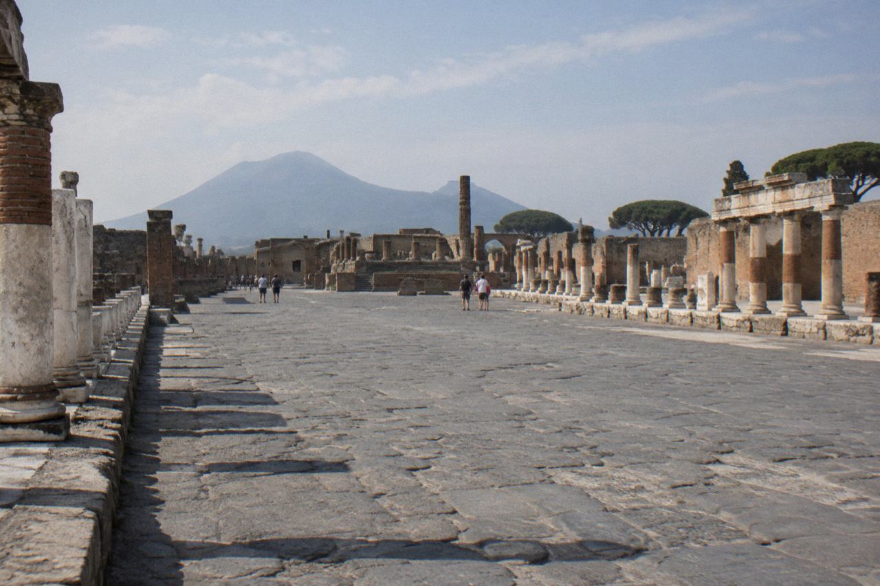 Shaded souvenir stalls and stall awnings along the street outside an entrance to the ancient city of Pompeii