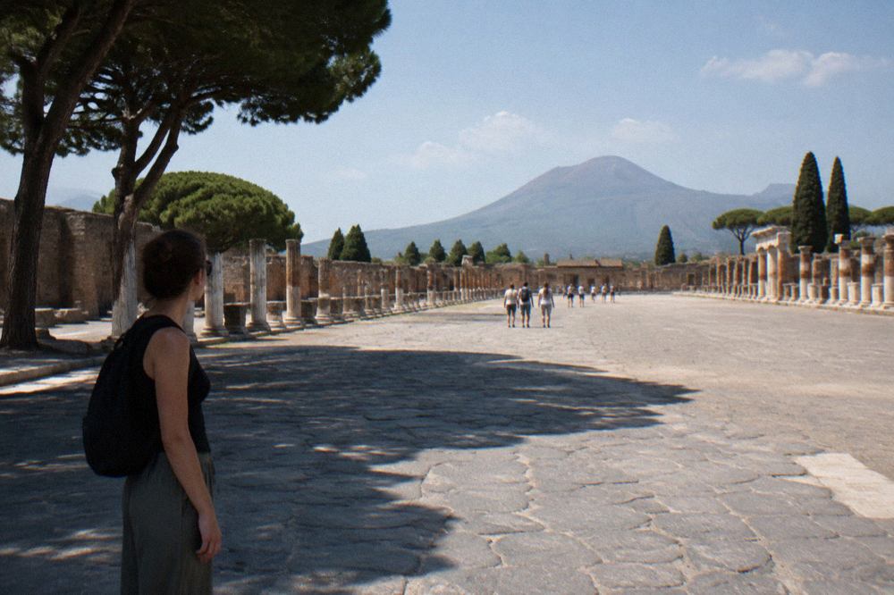 Empty stone street in the excavated ruins of Pompeii with Mount Vesuvius in the distance