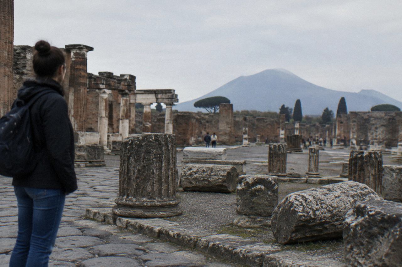 Empty stone street in the excavated ruins of Pompeii with Mount Vesuvius in the distance