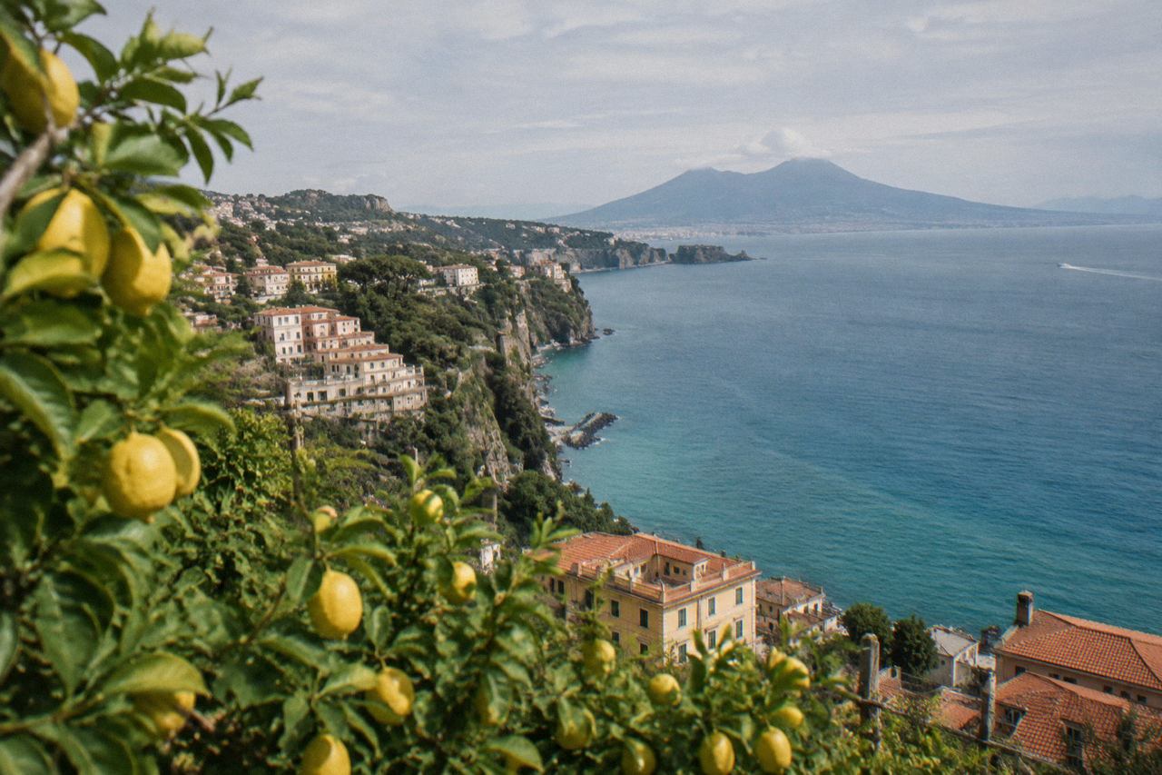 Pastel-coloured buildings on a cliff above the Bay of Naples with a harbour below