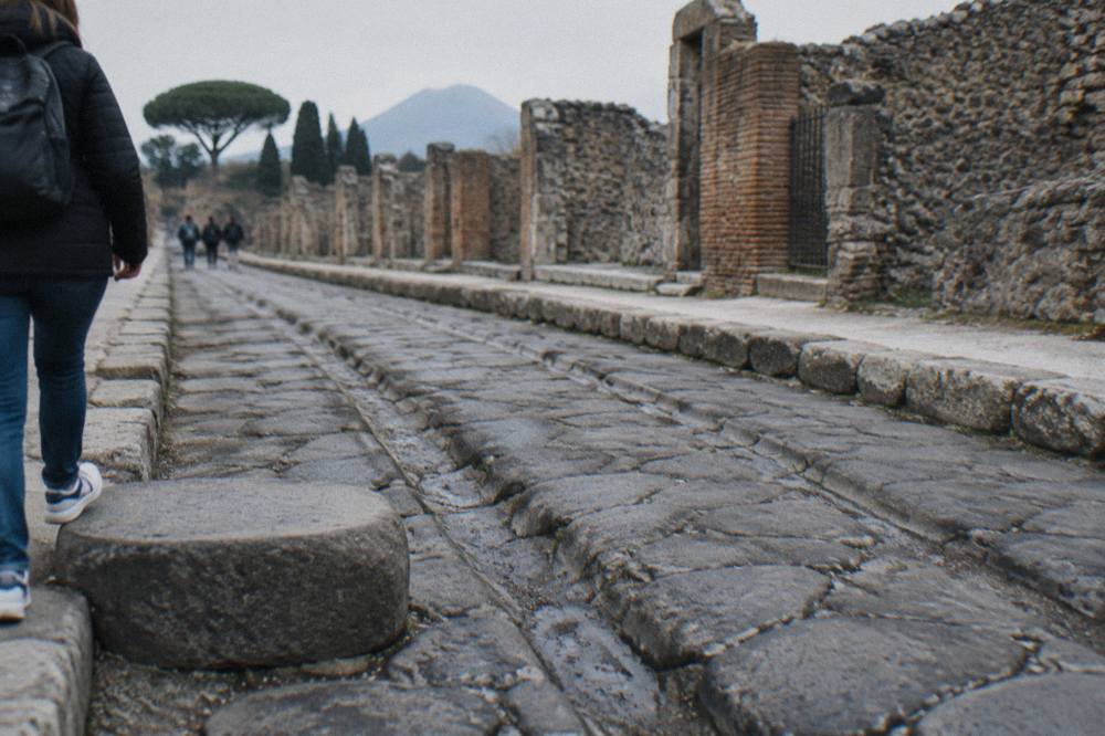 Ancient stone street in Pompeii lined by ruined walls under a clear sky