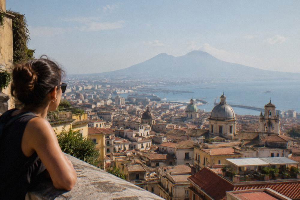 A narrow Naples street with tall pastel buildings and laundry strung between balconies