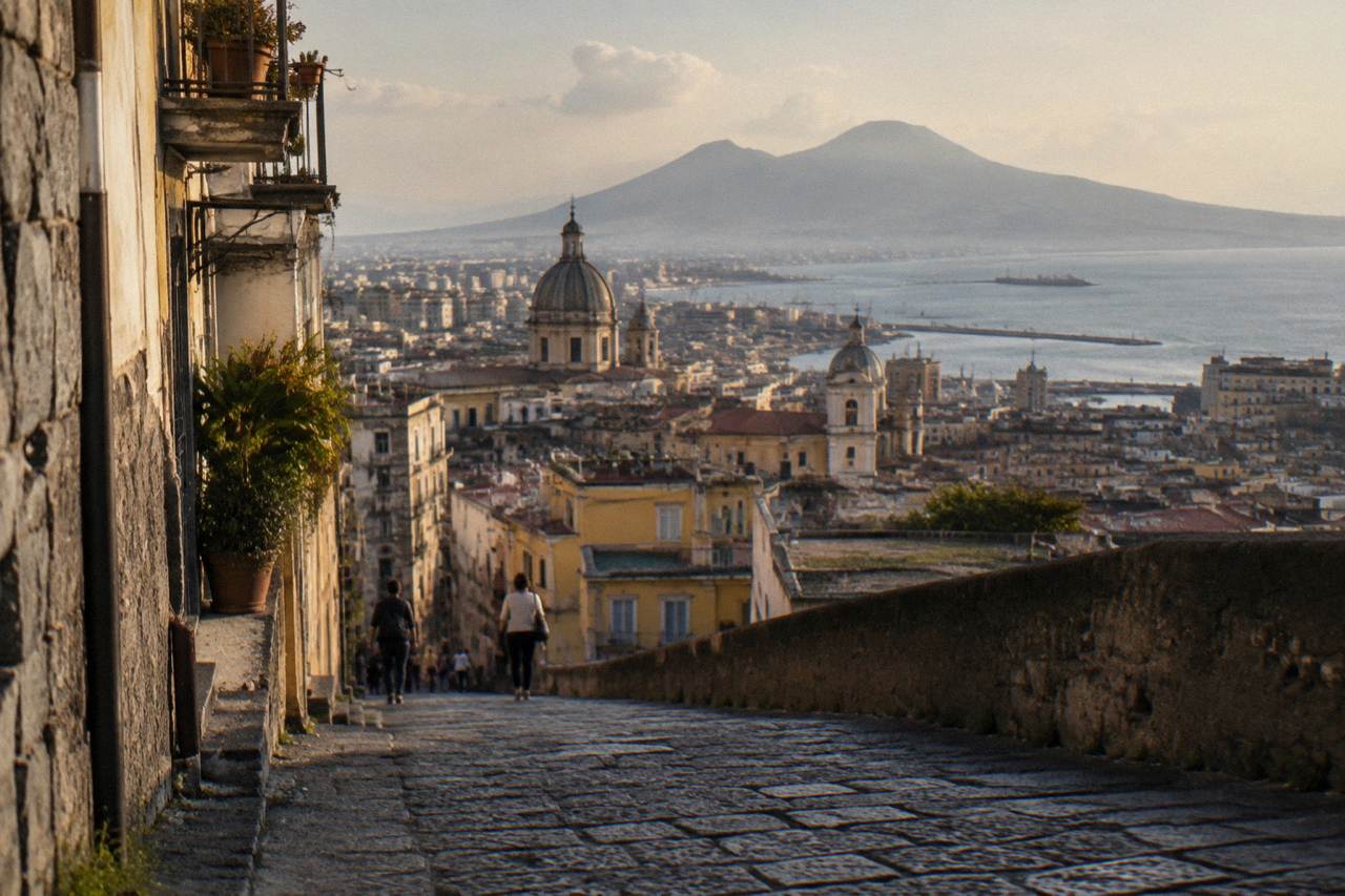 A narrow Naples street with tall pastel buildings and laundry strung between balconies