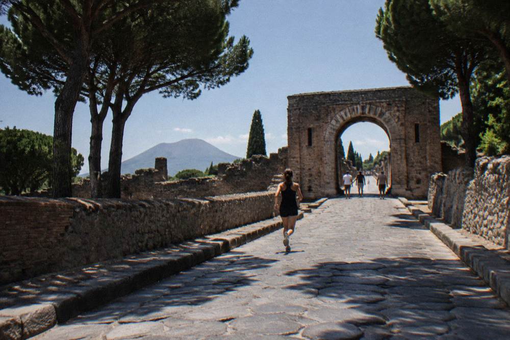 Ancient stone street in Pompeii with worn paving stones and ruined walls under a clear sky