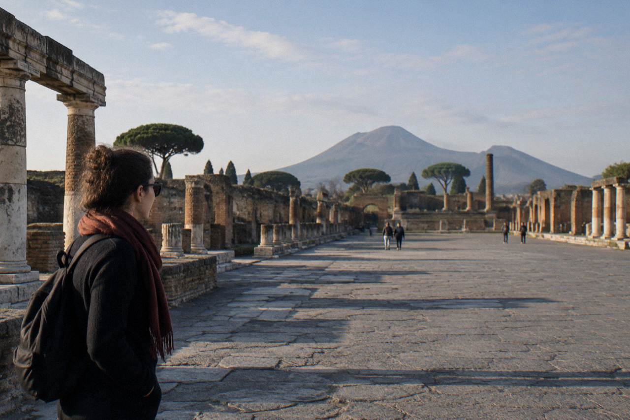 Ancient stone-paved street in Pompeii with wheel-worn ruts and ruined walls under a clear sky
