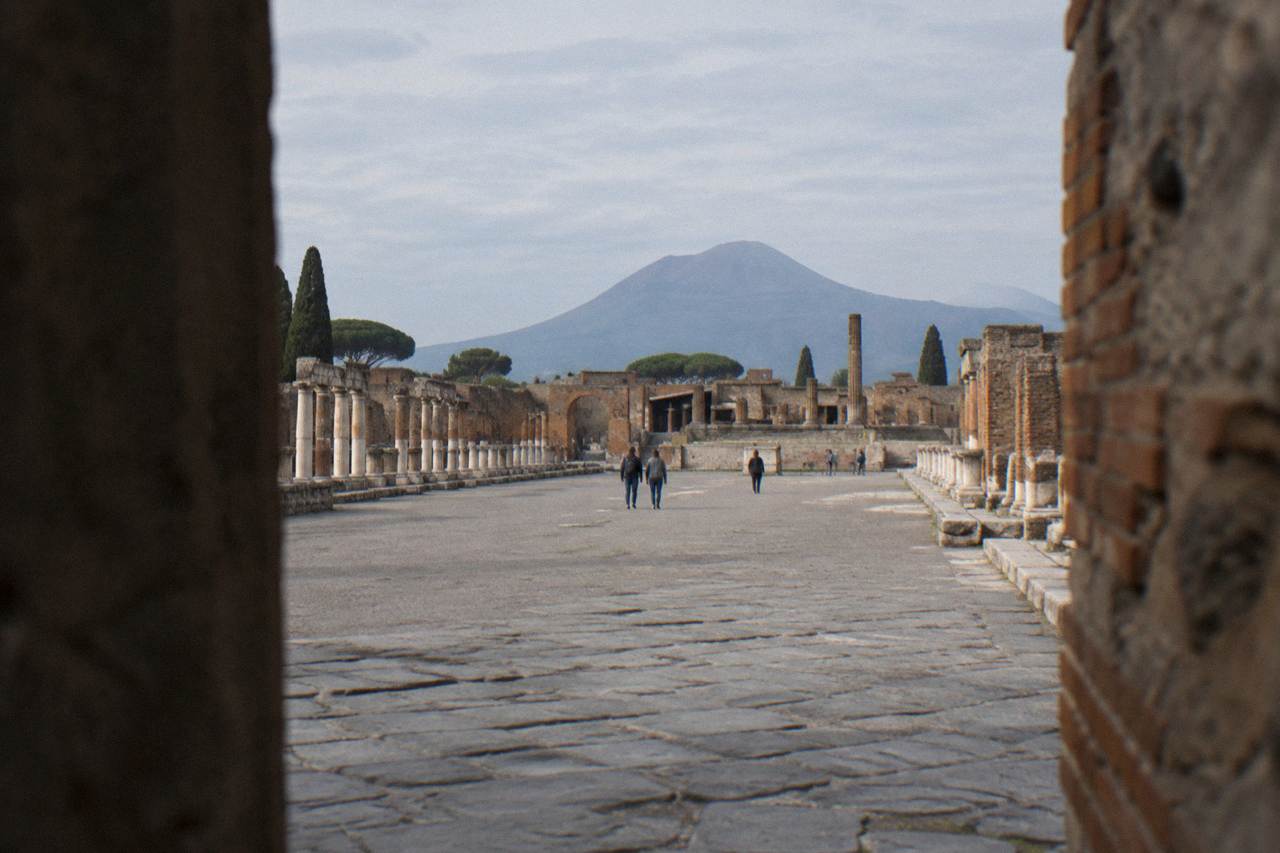 Bronze dancing faun statue standing on a rectangular pool in the ruined courtyard of the House of the Faun at Pompeii
