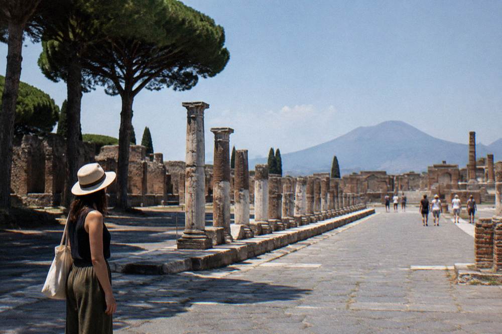 A stone-covered ancient street in Pompeii with worn Latin inscription panels set into a low wall