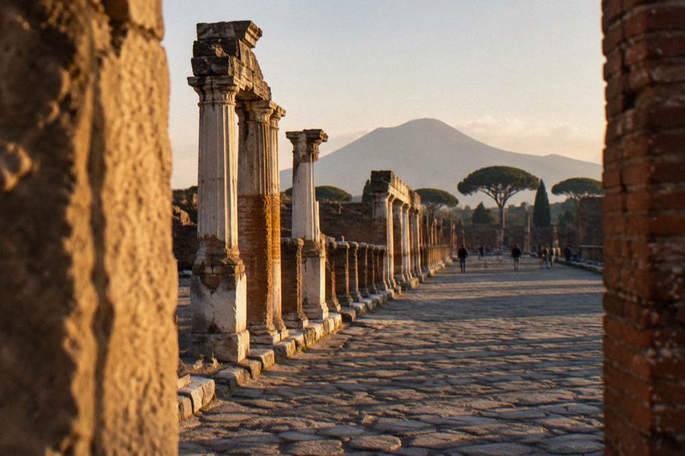 Excavated stone street of ancient Pompeii with Mount Vesovius rising behind the ruins