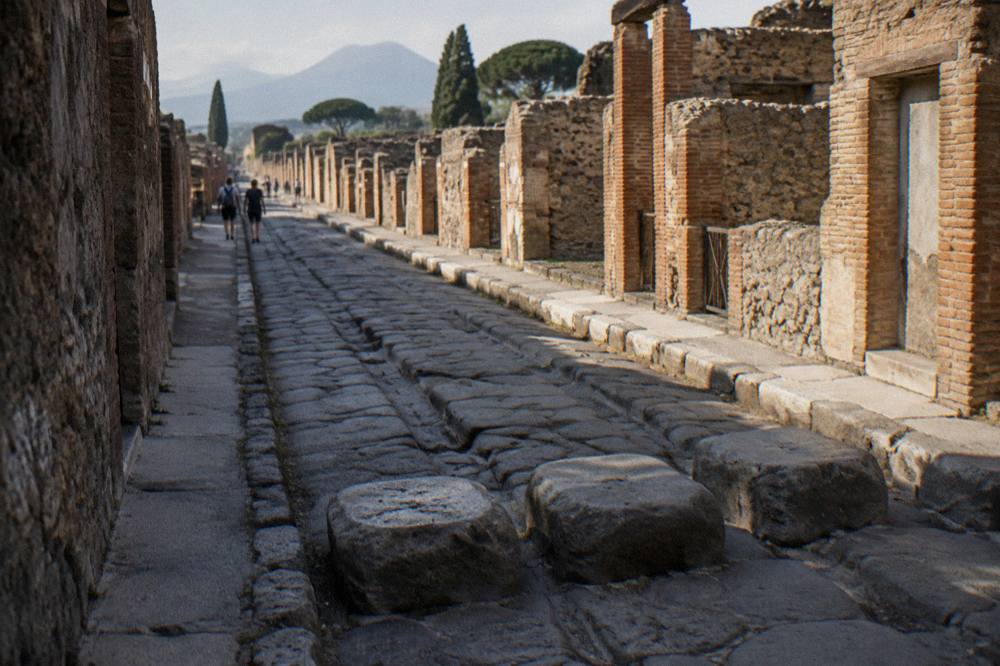 Ancient stone paving and ruined walls of Pompeii with Vesuvius rising in the distance on a clear day