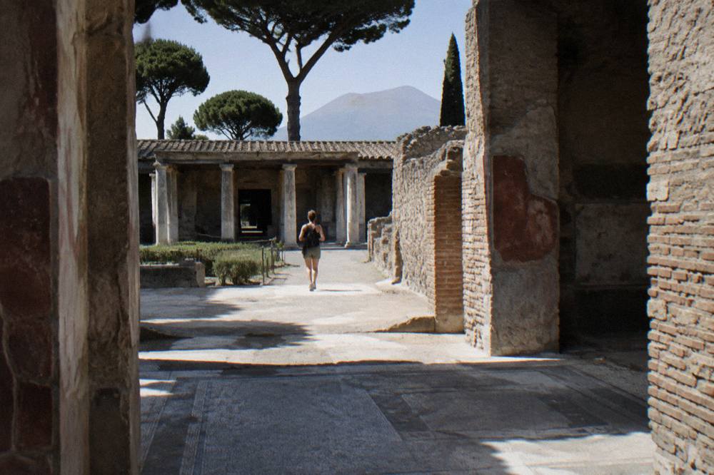 A stone-paved Roman street inside the excavations with ancient walls on both sides under morning light