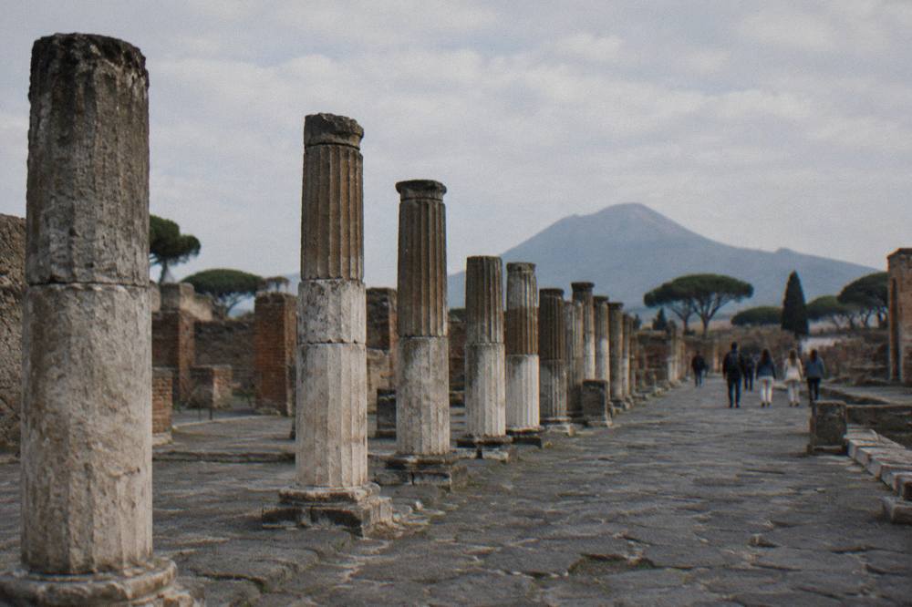 Stone-paved ancient street in Pompeii with the slopes of Vesuvius rising in the background