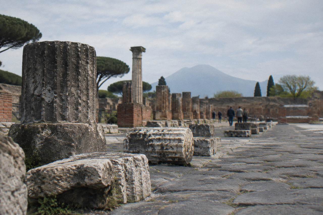 Empty stone street in Pompeii with worn stepping stones and ancient walls under a bright sky
