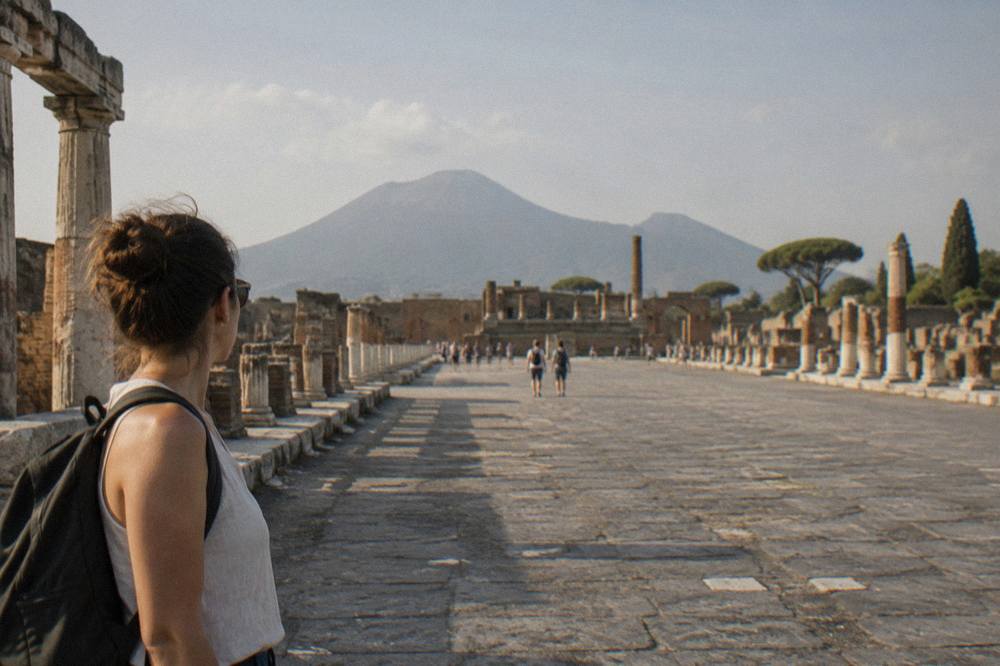Row of excavated Pompeii rooftops and walls seen from above with the unexcavated green plateau stretching beyond