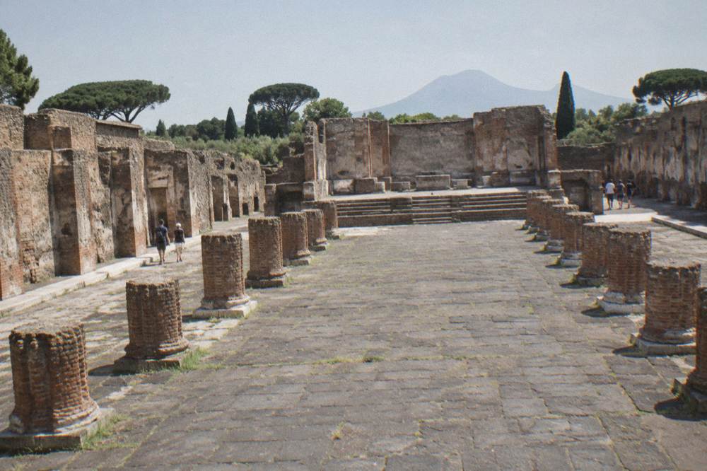 The ruined brick interior of the Basilica at Pompeii with rows of column bases receding into shadow
