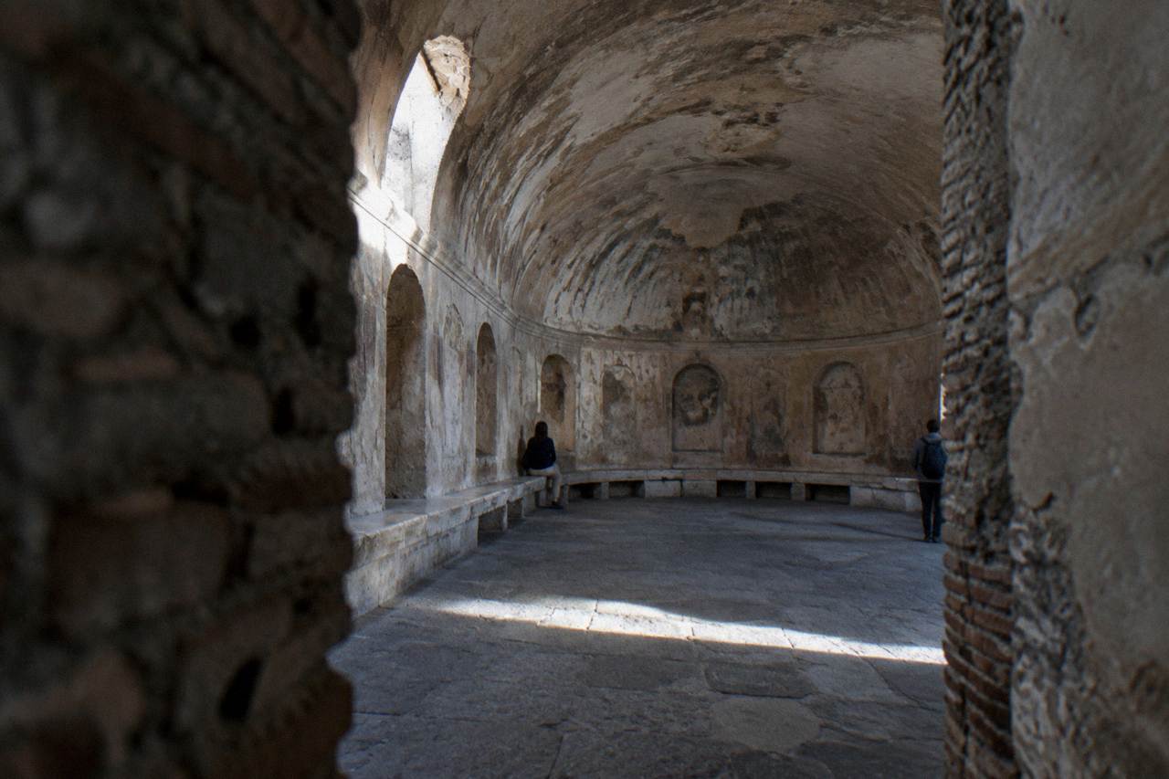 Ancient stone bathing hall with vaulted ceiling and light wells at the Forum Baths of Pompeii