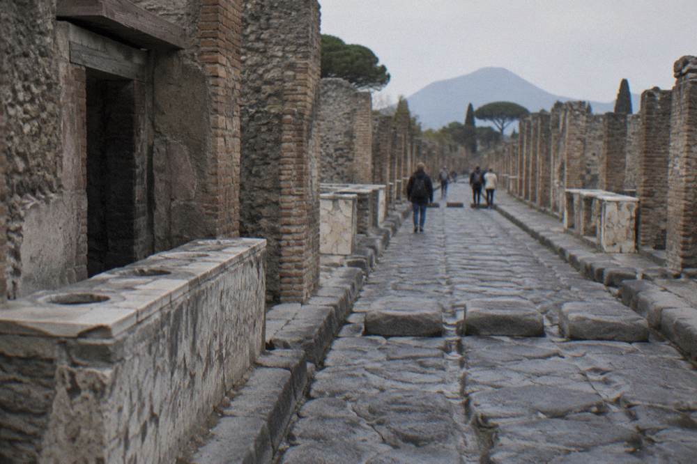 The interior of a large roofless ancient hall with tall brick columns and arches, the basilica law court of Pompeii