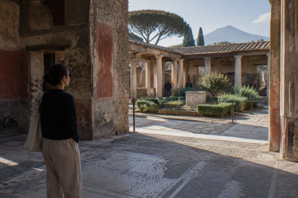 Glass cases containing human-shaped plaster casts standing on gravel in a Pompeian garden