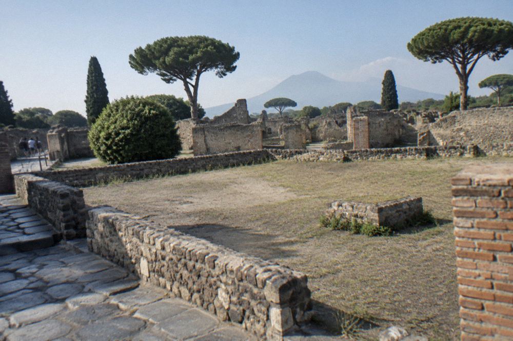 A quiet stone-paved lane between ruined walls leading toward the southwestern edge of Pompeii