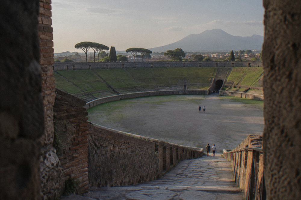 Guide and small group of visitors standing among weathered stone columns in Pompeii