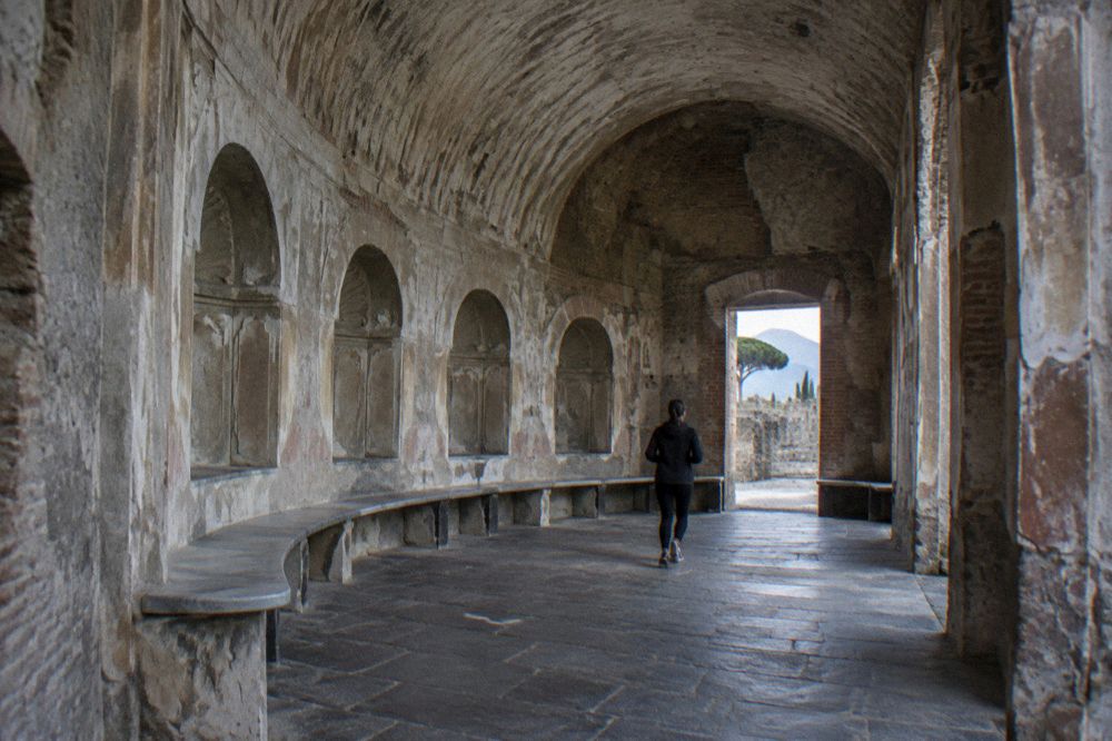Broad open plaza of the ancient forum with columns and Mount Vesuvius in the distance