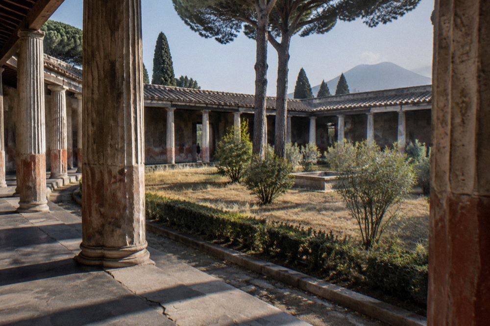 Narrow ancient stone street with worn paving stones between ruined walls in Pompeii