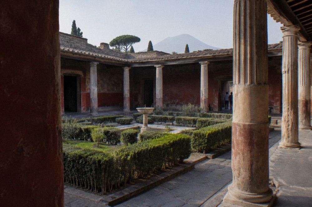 Wide view across the excavated Roman city toward the volcano Vesuvius at golden hour