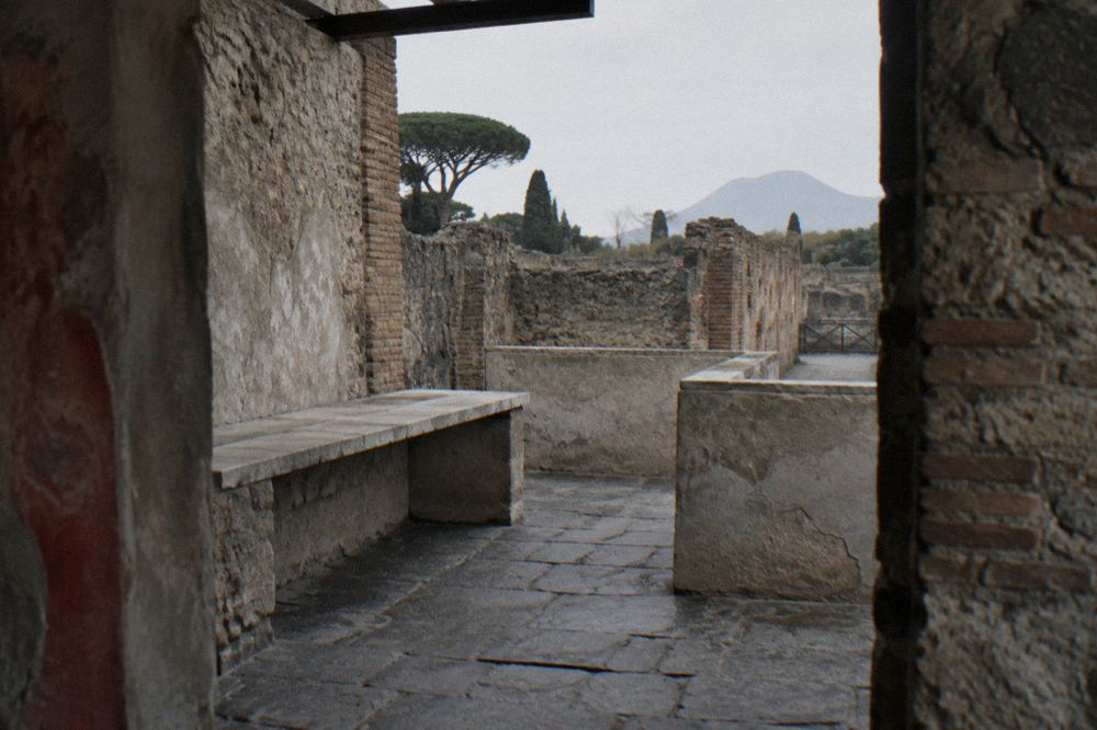 Long stone-paved Roman street with worn wheel ruts running between ruined walls in Pompeii
